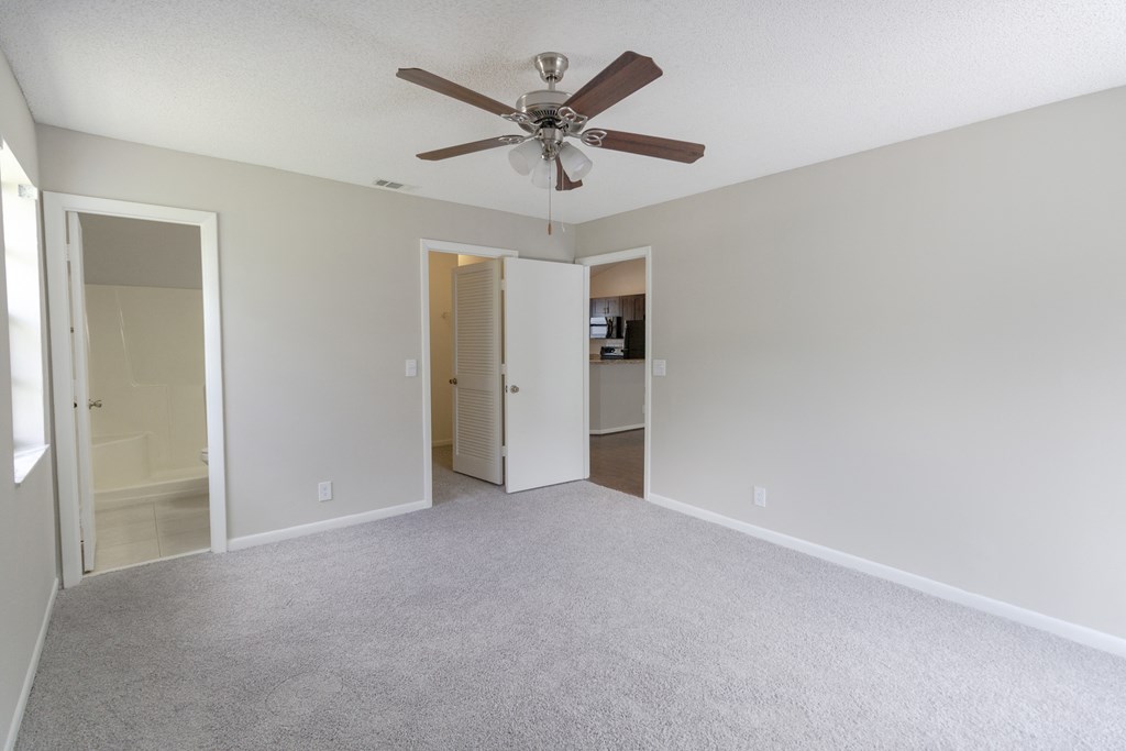 A room with a ceiling fan and carpeted floor.